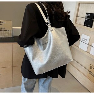 Close-up of metallic silver tote bag featuring lychee texture and slim metal bar detail