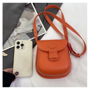 Detail of orange PU leather mini crossbody bag with vertical pleated texture and phone