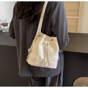 Minimalist cream white drawstring bucket bag shown on a model in a cozy coffee shop