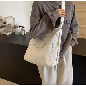 Detail of cream large crossbody bag with side zippers and wide canvas shoulder strap