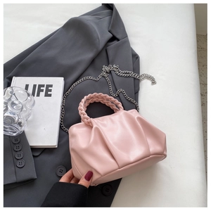 Detail of light pink pleated leather handbag with woven handle and silver chain strap