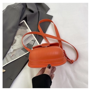 Detail of a bright orange crossbody bag with textured vertical stripes and shell-like design