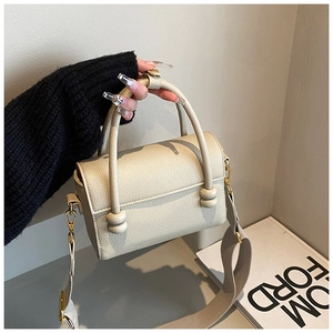 Détail du sac à main beige à motif litchi avec poignée nouée cylindrique et bandoulière