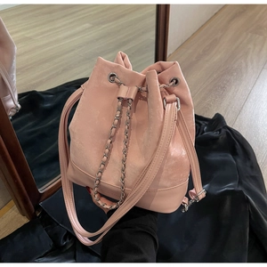 Pink drawstring bucket bag with chain detail and suede texture shown in a mirror
