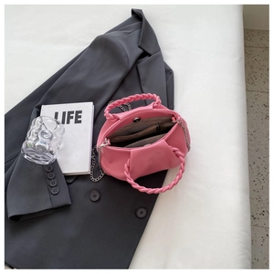 Detail of pink pleated cloud bag showing woven handle, chain strap and magnetic closure