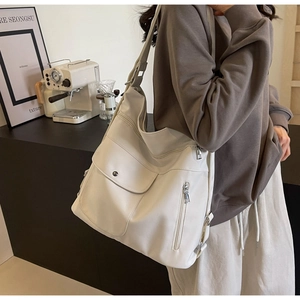Detail of cream large Hobo shoulder bag featuring a front snap pocket and side zip pockets