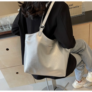 Detail of silver textured leather tote bag featuring a metallic bar and adjustable strap