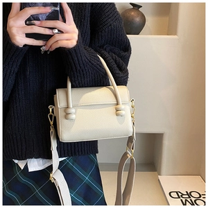 Détail du petit sac carré blanc cassé avec nœuds en cuir et bandoulière large ajustable