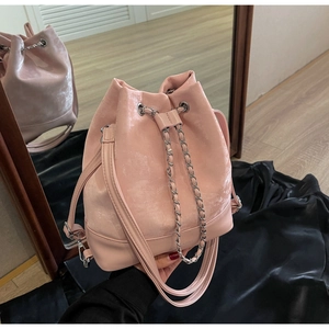 Detailed view of pink drawstring bucket bag featuring silver chain and glossy ripple texture