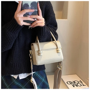 Détail du sac à main beige grainé avec bandoulière tissée large et nœud décoratif