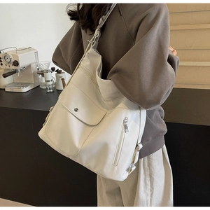 Detail of a large off-white hobo bag showing the flap front pocket and side zipper texture