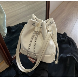 Detail of off-white bucket bag featuring drawstring chain closure and bottom logo embossed