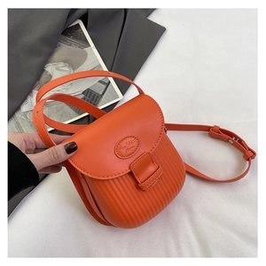 Detail of orange crossbody bag featuring vertical stripe texture and fashion embossing