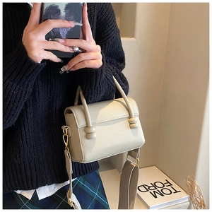 Détail du sac beige motif litchi avec poignée à nœud sphérique et bandoulière large