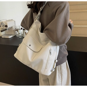 Detailed view of cream tote bag with multiple zip pockets and adjustable strap