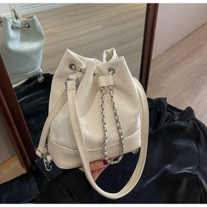 Detail of cream bucket bag with chain drawstring and elegant brand logo on smooth leather