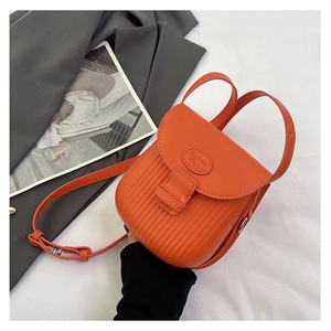 Detailed view of orange crossbody bag with vertical textured stripes and logo flap