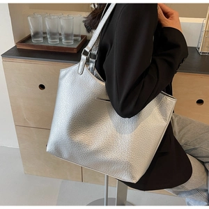 Detailed macro view of metallic silver tote bag featuring lychee texture and soft leather