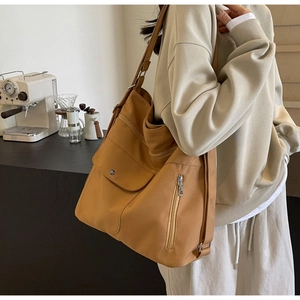 Detail of large canvas shoulder bag with multi-pocket design on a lifestyle model