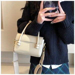 Détail du mini sac carré en cuir litchi crème avec ferrures dorées et large bandoulière