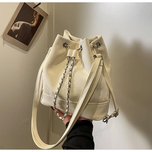Detail of white leather bucket bag with silver chain strap and drawstring closure
