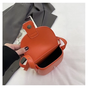 Detailed close-up of vibrant orange crossbody saddle bag showing leather texture and flap interior