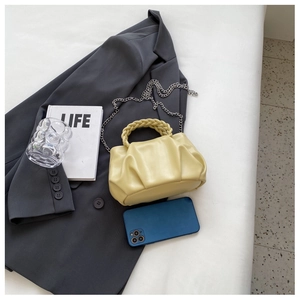 Detailed macro view of yellow pleated cloud bag with soft PU leather and woven handle texture