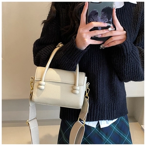 Détail du sac à main en cuir crème avec nœuds décoratifs et finitions dorées