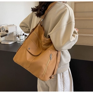 Detail view of tan nylon tote bag showing flap pockets and adjustable metal buckle