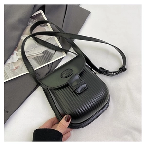 Detail of black crossbody bag featuring vertical pleated texture and smooth flap cover