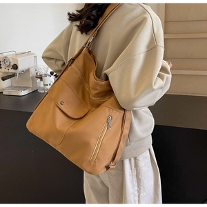 Detail view of large camel brown tote bag with multi-zipper pockets and shoulder strap