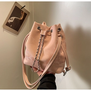 Detailed view of pink drawstring bucket bag with metal chain and leather strap