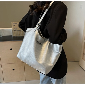 Side view of large silver tote bag showing its metallic texture and soft drape on shoulder