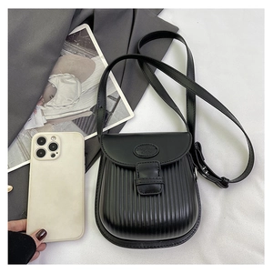Detail of black crossbody bag with vertical stripe embossing and adjustable strap