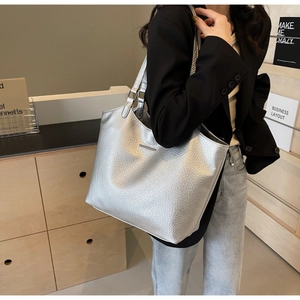 Detailed view of silver textured leather tote bag with metallic plate and sturdy handles