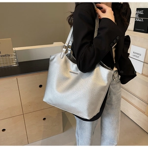 Silver metallic leather tote bag with pebble texture carried on shoulder by a model