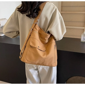 Detail of khaki crossbody bag featuring multiple zipper pockets and adjustable wide strap