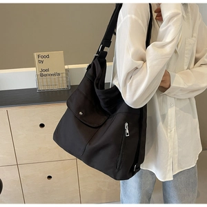 Macro view of large black tote bag with functional pockets and adjustable wide nylon strap