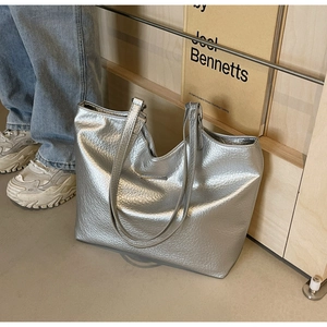 Detail view of silver tote bag featuring lychee grain texture and metal logo plaque