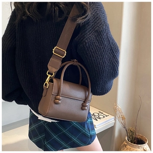 Détail du sac marron en cuir grainé avec finitions dorées et bandoulière large