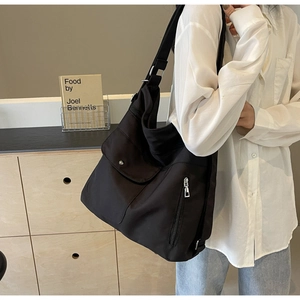 Macro shot of large black multi-pocket shoulder bag with matte nylon fabric texture