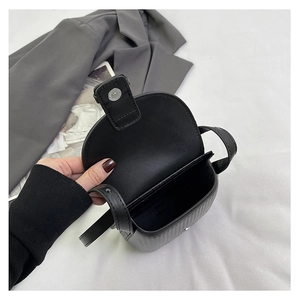 Interior view of black leather crossbody bag showing internal space and magnetic closure