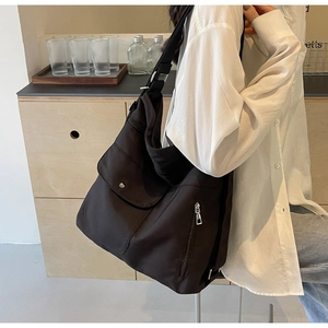 Close-up of black nylon shoulder bag featuring multiple pockets and durable metal buckles