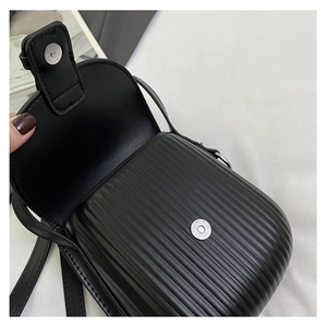 Detail of black mini crossbody bag with vertical stripe texture and silver magnetic buckle