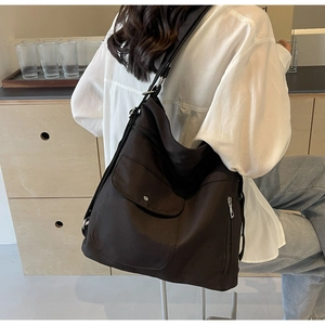 Detail view of large black nylon shoulder bag with front flap pocket and zipper design