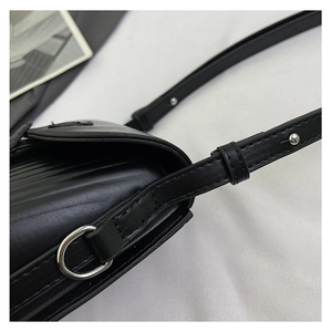 Detail of silver D-ring hardware and vertical textured leather on a black crossbody bag
