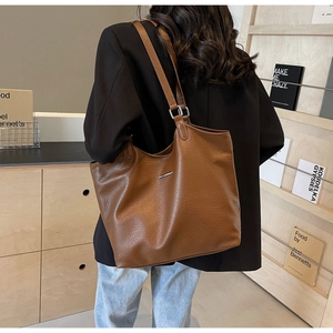 Detailed view of brown leather tote bag texture and elegant silver metal bar accent
