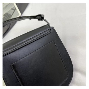 Detail of black leather shoulder bag showing the rear U-shaped pocket and silver hardware