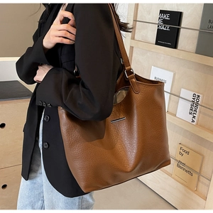 Close-up showing the pebbled leather texture and silver metal detail on a brown tote bag