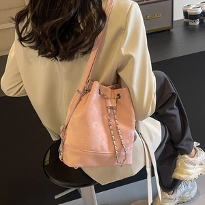 Pink drawstring bucket backpack with metal chain and matte texture shown on a model